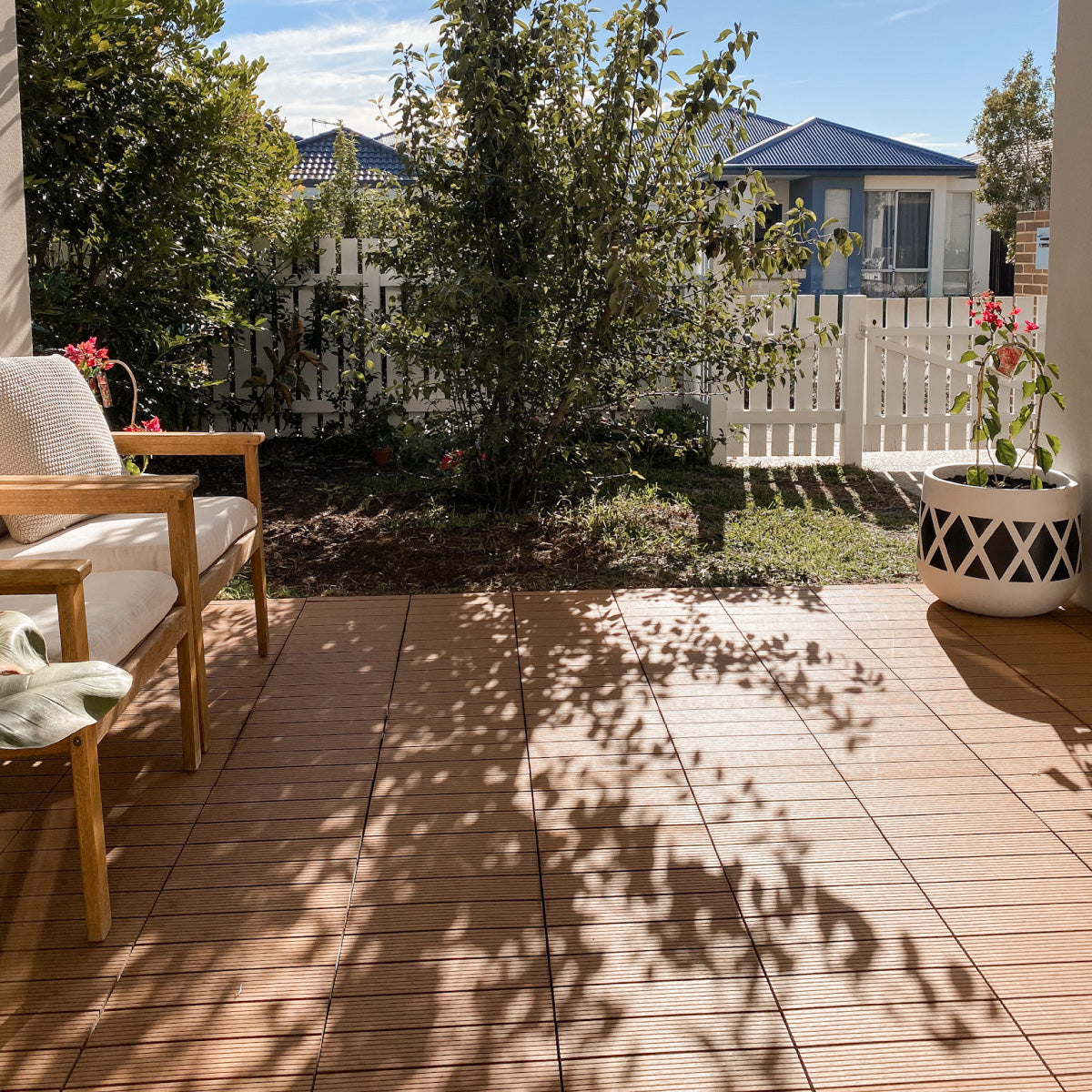 Cozy outdoor patio with teak patio tiles and wooden chair, creating a warm and natural flooring look for garden and backyard spaces 